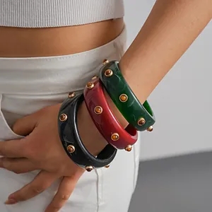 Close-up of vintage-style resin bangles with circular rivet studs in bold colors
