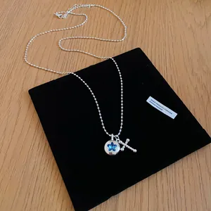 Detailed macro shot of silver bead necklace with blue star pendant and stylish cross charm
