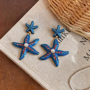Eleganti orecchini a stella marina blu da spiaggia con strass rossi e perle centrali