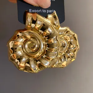 Primo piano di orecchini vintage a forma di nautilus dorati con una finitura lucida
