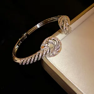 Detailed close-up of a silver-toned open bangle with twisted zircon knot design