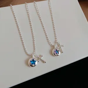 Detail shot of silver bead chain necklace with blue star crystal and cross pendant