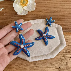 Eleganti orecchini pendenti a stella marina blu con strass rossi e perla