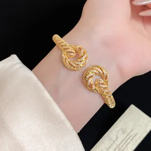 Detailed macro view of an 18K gold-plated cuff bracelet with zircon twisted pattern.