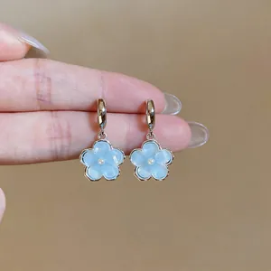 Macro view of sweet blue resin flower drop earrings featuring small pearl centers
