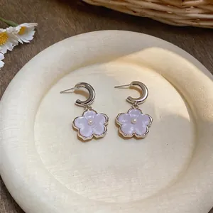 Macro view of sweet purple resin flower pendant earrings with delicate pearl centers