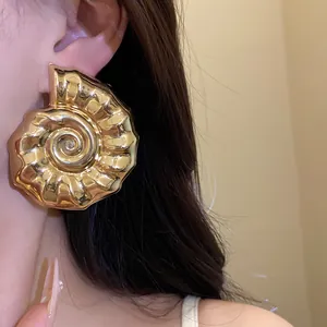 Dettaglio di orecchini eleganti a forma di lumaca in oro metallizzato lucido brillante