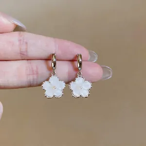 Macro close-up detail showing sweet white resin flower dangle earrings with pearl