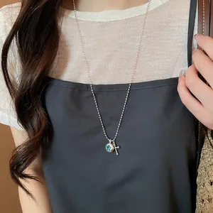 Detailed view of a silver bead chain necklace with star and cross pendants on a model