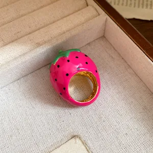 Detailed macro shot of pink enamel strawberry ring featuring golden interior and green leaves