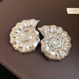 Dettaglio ravvicinato di orecchini a conchiglia argento con finitura lucida