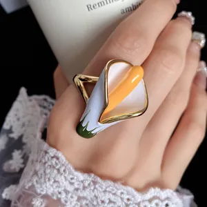 Detailed view of an elegant calla lily flower ring with white enamel and gold finish