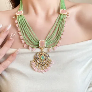 Vintage multi-strand green beaded necklace with ornate gold-tone pendant and pink accents