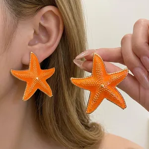 Vibrant orange starfish ear studs with gold trim for summer beach vacation style.