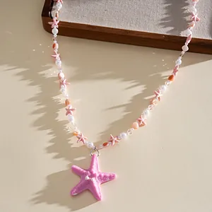 Détail du pendentif étoile de mer en résine rose et chaîne perlée pour collier d'été.