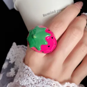 Close-up detail of a vibrant pink strawberry enamel ring featuring a cute fruit design.