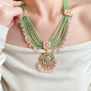 Close-up of vintage multi-layered green beaded necklace with ornate gold pendant for women