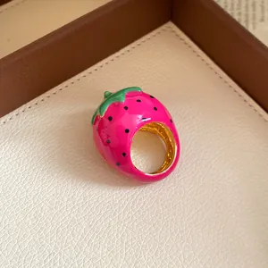 Detailed view of the vibrant pink enamel strawberry ring with gold-tone band