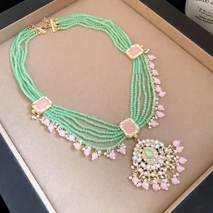Detailed view of multi-strand green beaded necklace with pink accents and ornate pendant.