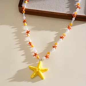 Gros plan détaillé d'un pendentif étoile de mer en résine jaune avec des perles colorées.