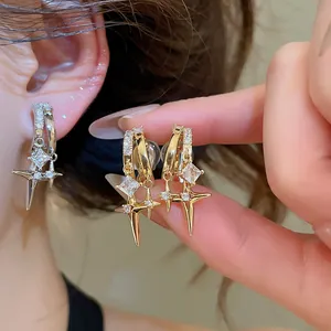 Close-up of 18k gold plated zircon double star ear clips worn on ear and held by fingers