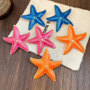 Close-up of vibrant enamel starfish stud earrings in blue, pink and orange colors.