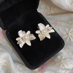 Pendientes de flores doradas con pétalos de esmalte blanco, perlas y circonitas brillantes
