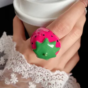 Close-up of a cute pink strawberry ring with green leaf detail and glossy finish.
