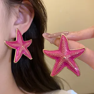 Detailed view of large pink starfish-shaped stud earrings with exquisite gold bead trim