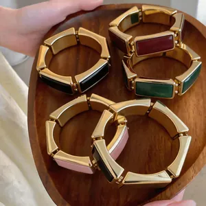 Collectie vintage gouden rechthoekige armbanden met kleurrijke emaille inlays op dienblad