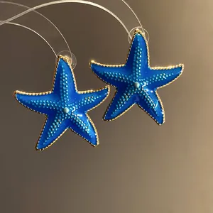Detailed view of blue enamel starfish earrings with gold-toned edges and dotted texture