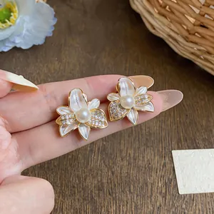 Vista detallada de pendientes de botón con forma de flor, pétalos de esmalte y perla