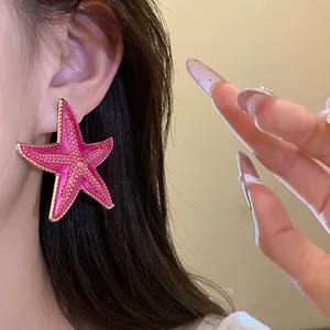 Detailed macro view of a vibrant pink starfish earring with textured gold-tone edges.