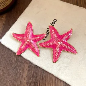Detailed close-up of vibrant pink enamel starfish stud earrings with gold trim.