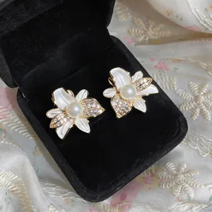 Vista macro de exquisitos pendientes de flores con perlas blancas y circón en caja negra