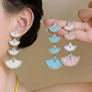 Detailed view of multi-tiered fan-shaped dangling earrings with shimmering zircon