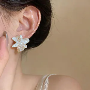 Primer plano de elegantes pendientes de flor con circonitas y perla en el modelo