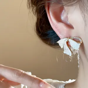 Detailansicht eines eleganten weißen Schleifen-Ohrsteckers mit Zirkonia-Steinen