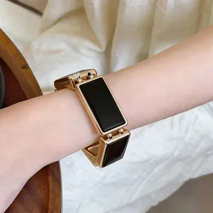Detailopname van een vintage goud en zwart rechthoekig schakelarmbandje om een pols.