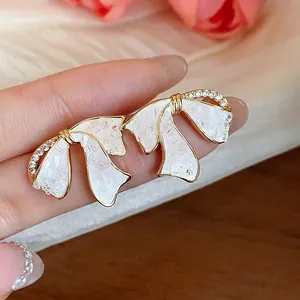 Nahaufnahme von eleganten Schleifen-Ohrringen mit Zirkonia und weißer Emaille-Füllung.