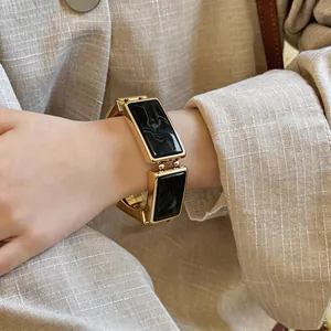 Detailopname van een vintage goudkleurige rechthoekige armband met zwarte harsinzetstukken
