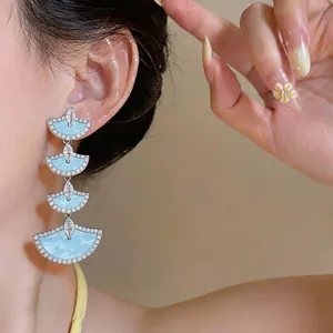 Close-up of cascading light blue fan-shaped earrings with sparkling cubic zirconia pavé.