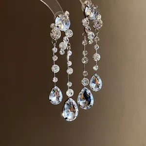 Detaillierte Nahaufnahme eleganter silberner Hängeohrringe mit funkelnden Wassertropfen-Kristallen