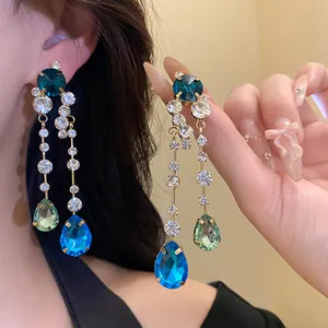 Nahaufnahme eleganter Strass-Ohrhänger mit blauen tropfenförmigen Kristallen.