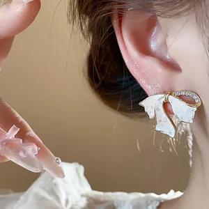 Detailaufnahme eines 18 Karat vergoldeten Schleifenohrsteckers mit Zirkonia am Ohr.