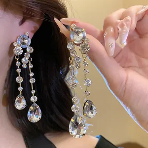 Nahaufnahme eleganter Strass-Wassertropfen-Ohrringe am Ohr mit funkelnden Kristalldetails.