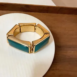 Close-up van vintage gouden chunky rechthoekige armband met donkere blauwgroene hars inlays