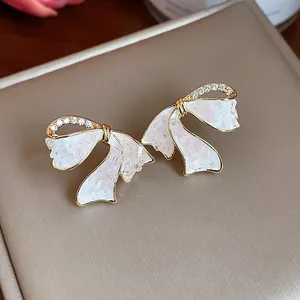 Elegante vergoldete Schleifen-Ohrringe mit Zirkonia-Steinen und schimmernden weißen Inlays