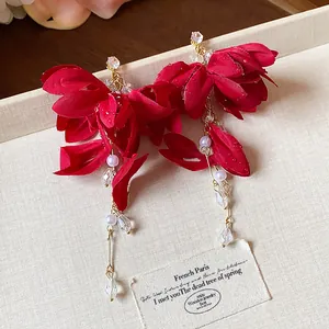 Close-up of red fabric flower earrings with elegant pearl and crystal tassel details
