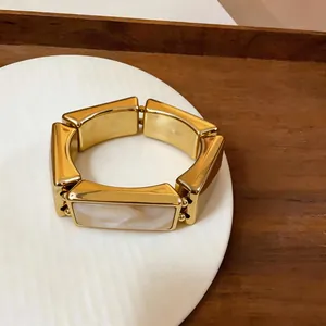Detailopname van een gouden retro rechthoekige armband met witte marmeren inleg
